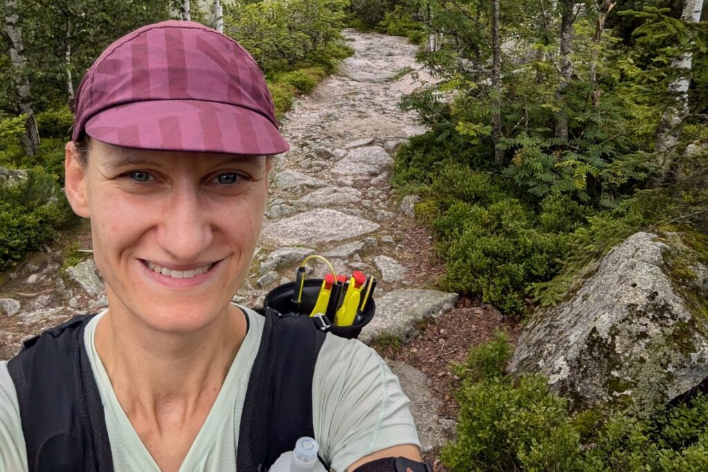 Trailrunnerin beim Ultratrail mit Stöcken im Rucksack, Selfie auf dem Trail